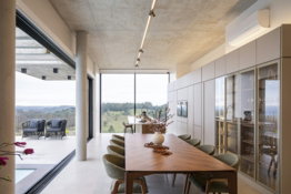 Modern dining room with expansive windows and scenic view.